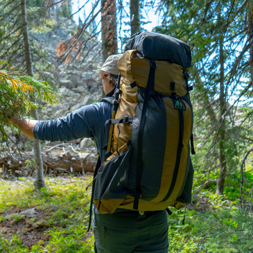 Backpacker trekking through green forest with a Divide 4800ci hiking pack