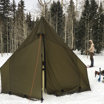 Snowy backcountry camp with Courthouse tent, 6-inch sod skirt sealing drafts, mountain valley backdrop