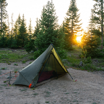 Seek Outside Brightwater 1P tent pitched in forest clearing, single trekking pole support, 101-108 inch width, green silnylon canopy