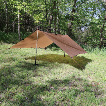 DST tarp set up in elevated A-Frame in a forest setting with green grass and green trees
