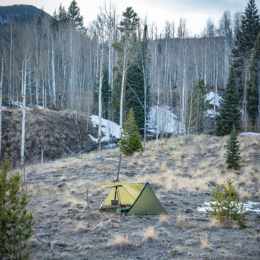 guardian 2.0 with awning open showing a wood burning stove and sleeping bag inside shelter