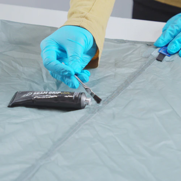 person uses silnet seam sealer on the seam of a tent