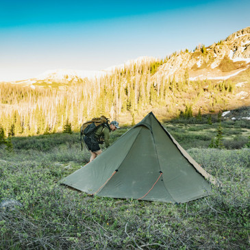 backpacker enters tent though full length zipper, peak vent open for ventilation 