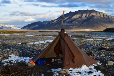 Backcountry camp with Seek Outside Cimarron shelter against dramatic peak backdrop, stove jack visible