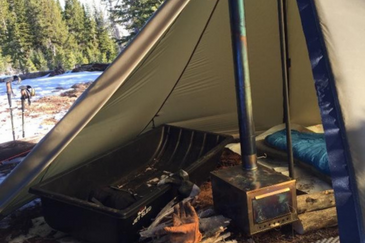 Cimarron hot tent with Seek Outside titanium stove installed, gear stored on opposite side