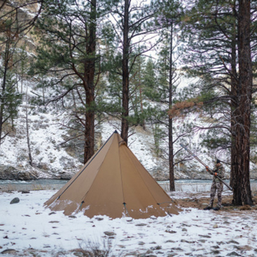 Seek Outside tipi tent pitched in snowy meadow with 8 foot 6 inch peak height, snow piled around sod skirt for insulation