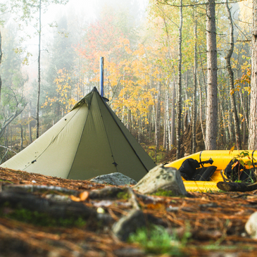 Seek Outside Redcliff hot tent pitched in a wet autumn forest showing angular panels shedding water and 6-inch sod skirt sealing out drafts