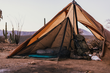 Cimarron Half Nest with sleeping bag inside and hunting pack, rifle, and gear in the tent area outside