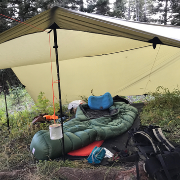 a sleeping pad and gear on a Matty ground mat inside a shelter
