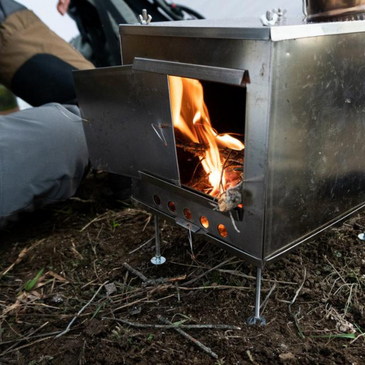 floorless tent with stove jack and titanium stove setup inside, flames visible and no floor beneath
