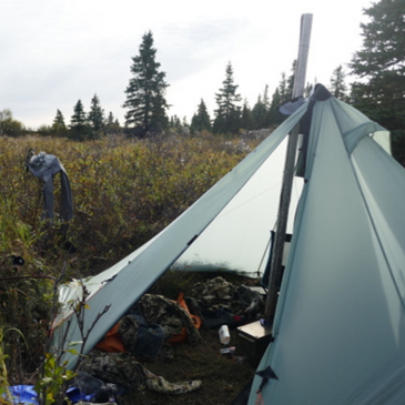 doors open on a Redcliff light pyramid tent revealing stove and camping gear inside