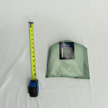 Lightweight cimarron liner in a stuff bag next to measuring tape to show compact size 