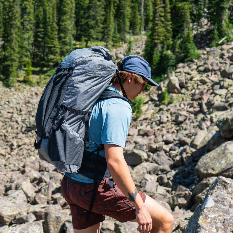 Backpacker with a loaded Flight 3 on a rocky high route, the abrasion-resistant Ultra fabric visible against the rock.