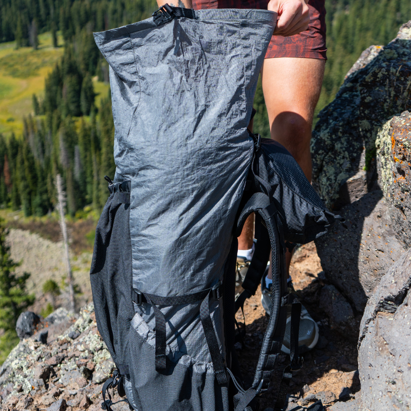 Backpacker adjusts the roll-top closure of a Flight 3 backpack