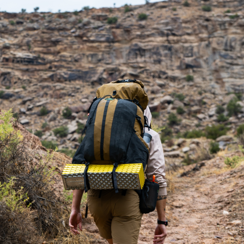 Hiker wearing a Divide 4800ci pack navigating a rocky, mud-slicked trail