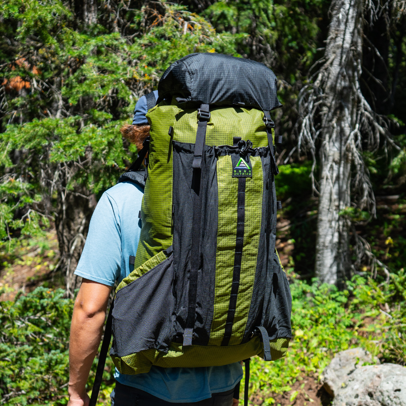 a hiker wears a a Divide backpack with top lid attached for extra storage