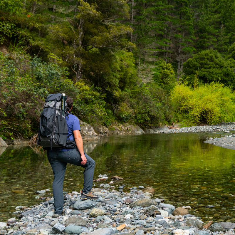 Backpacker with Goshawk 4800 crossing mountain stream, packbag highly water resistant, 1500mm hydrostatic head 