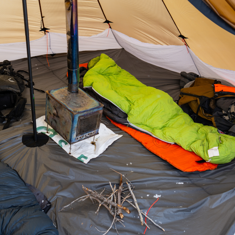 Winter camp inside Redcliff with Floor Liner, snow on ground, bathtub floor design preventing water intrusion, gear and stove inside