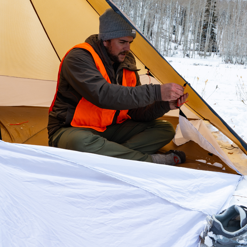 Hunter laying out Redcliff Floor Liner inside shelter, adjustable top liner attachments with linelocks, 21-inch wall liner, 20D breathable liner