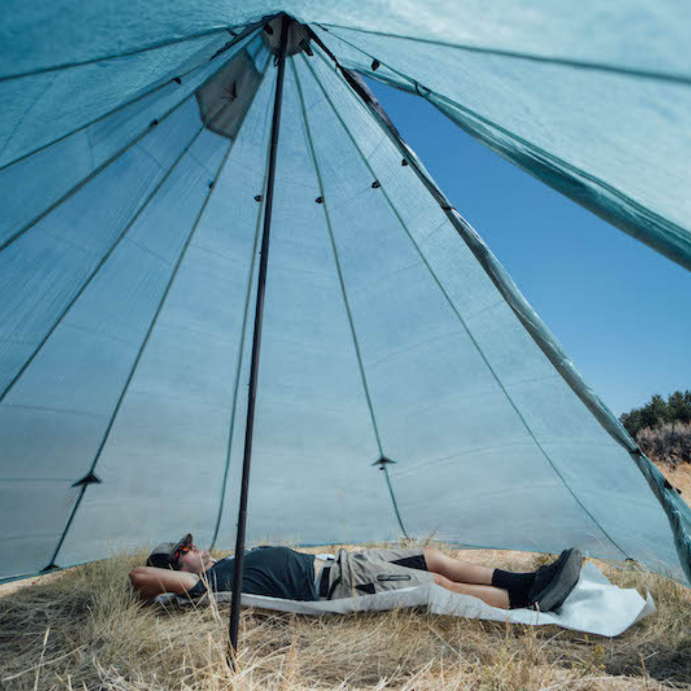 a man lays on a sleeping mat inside a redcliff ultralight hot tent