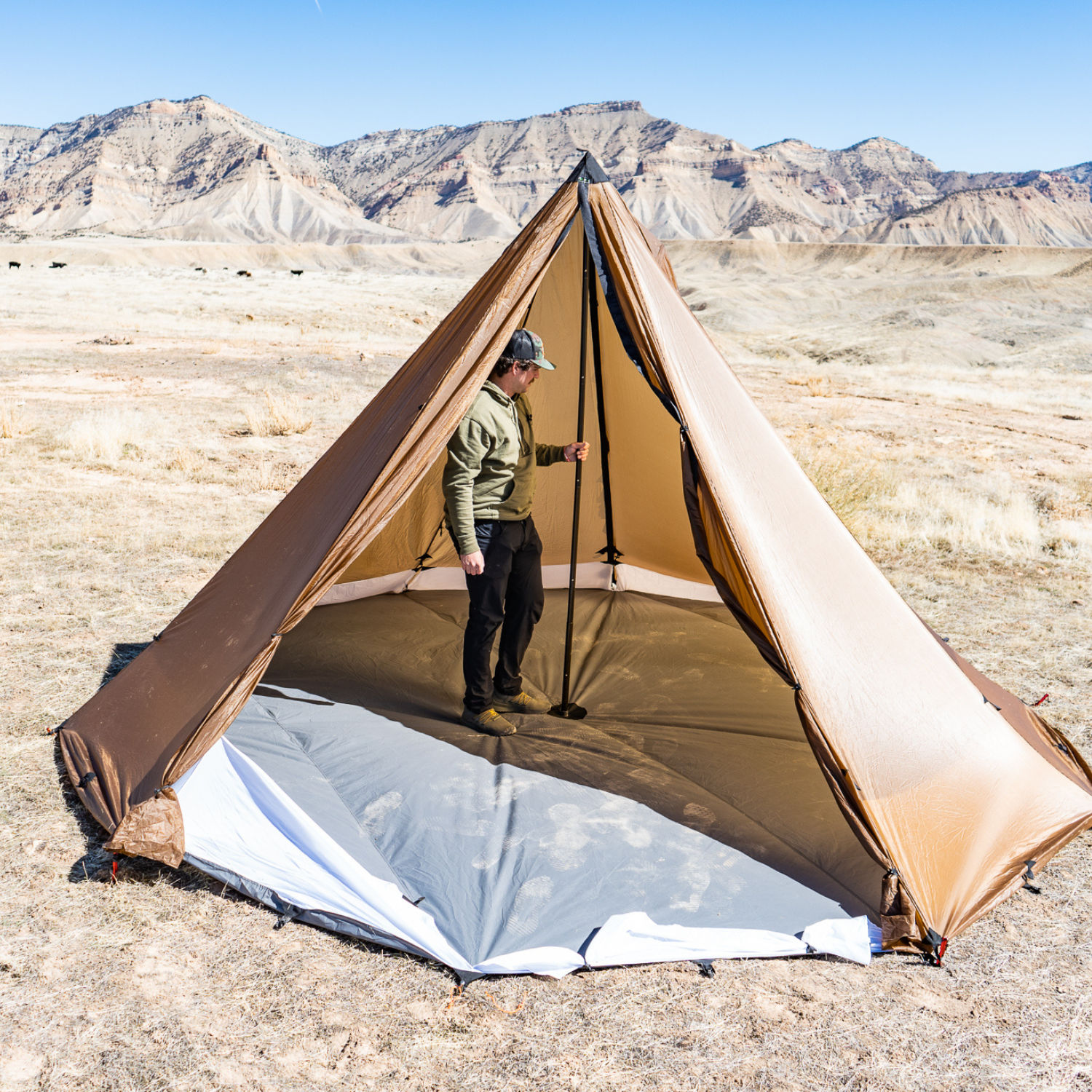 a man stands inside an 8 person tent with the floor liner system installed in the tent