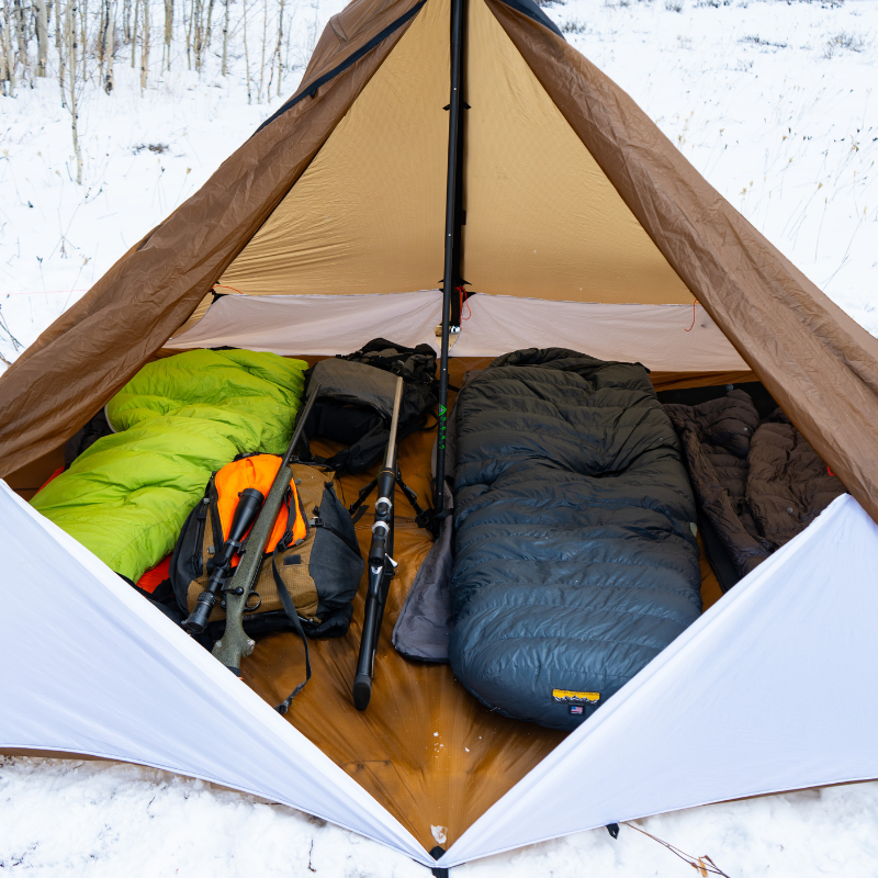 Hunting camp inside Cimarron with Floor Liner installed, sleeping pads, stove, rifles, and packs on 94 square feet waterproof floor