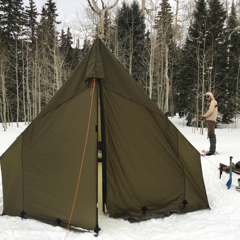 Snowy backcountry camp with Courthouse tent, 6-inch sod skirt sealing drafts, mountain valley backdrop