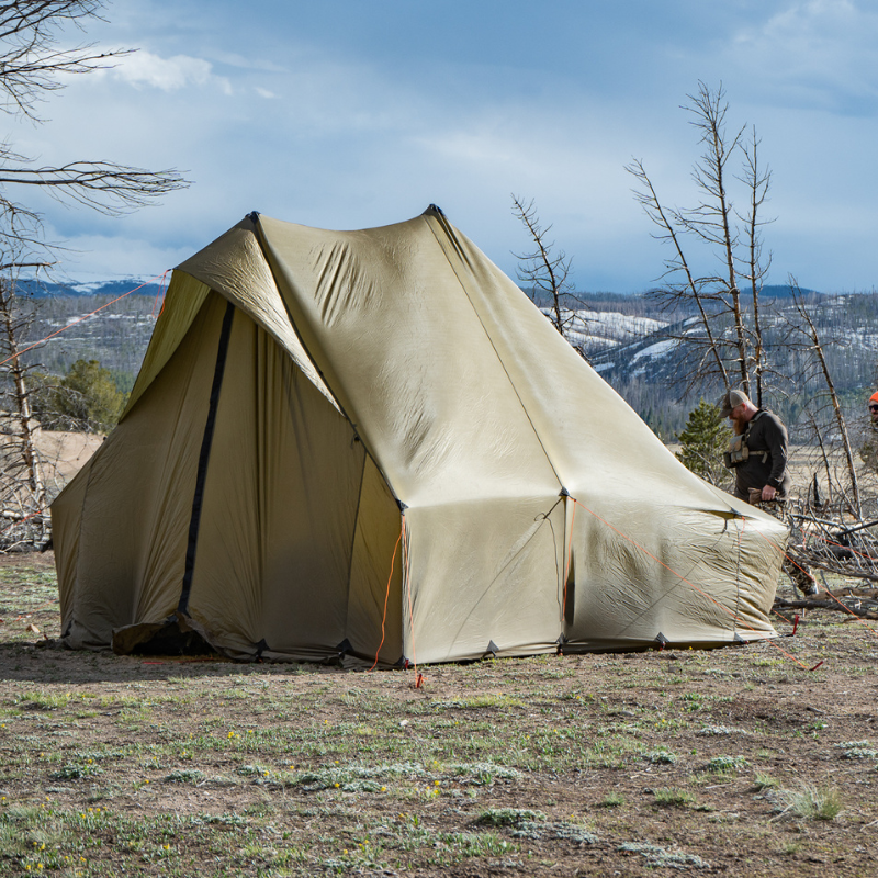 a Courthouse tent set up in a grassy clearing, hills in the distant background and clear blue skies