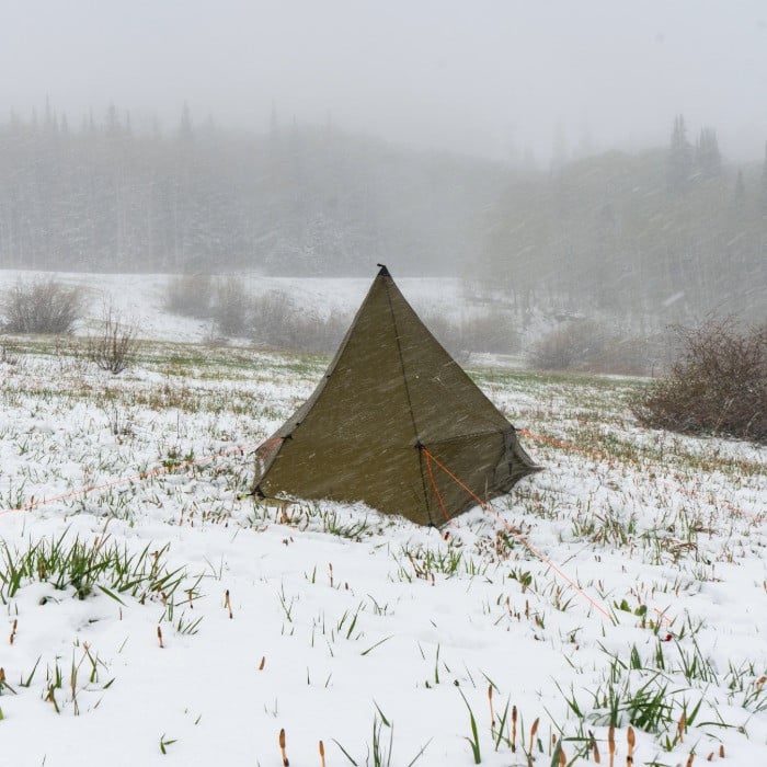 green Brightwater tent site in a snow covered valley, the background obscured with fog