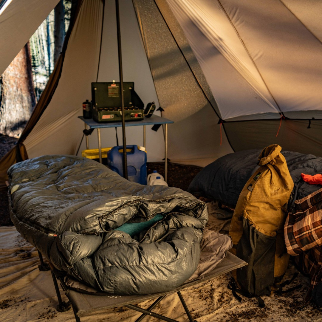bookcliff interior with two cots, sleeping gear, a backpack and a table with a camp grill inside the tent
