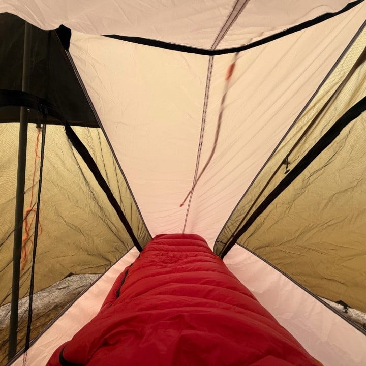 Backpacker inside Silex Nest with tent and nest door closed, DWR side walls and noseeum mesh protection