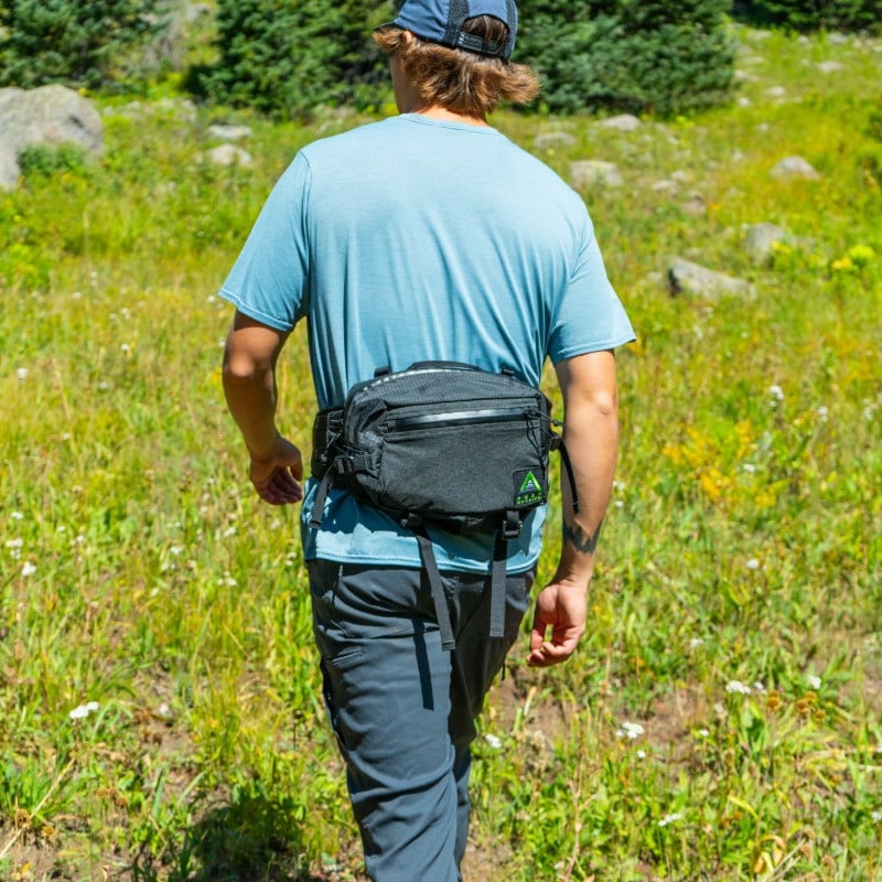 black mesa hip pack being used in a large alpine meadow being worn by man facing away
