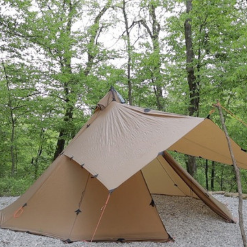 tipi tent with DST tarp attached as awning over dual zippered doors, providing covered gear storage and entry