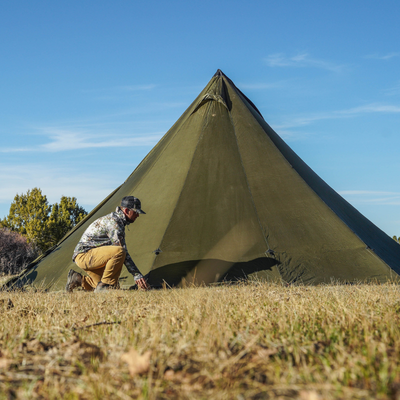 hunter adjusts the reinforced stake loops on 12 person tipi tent