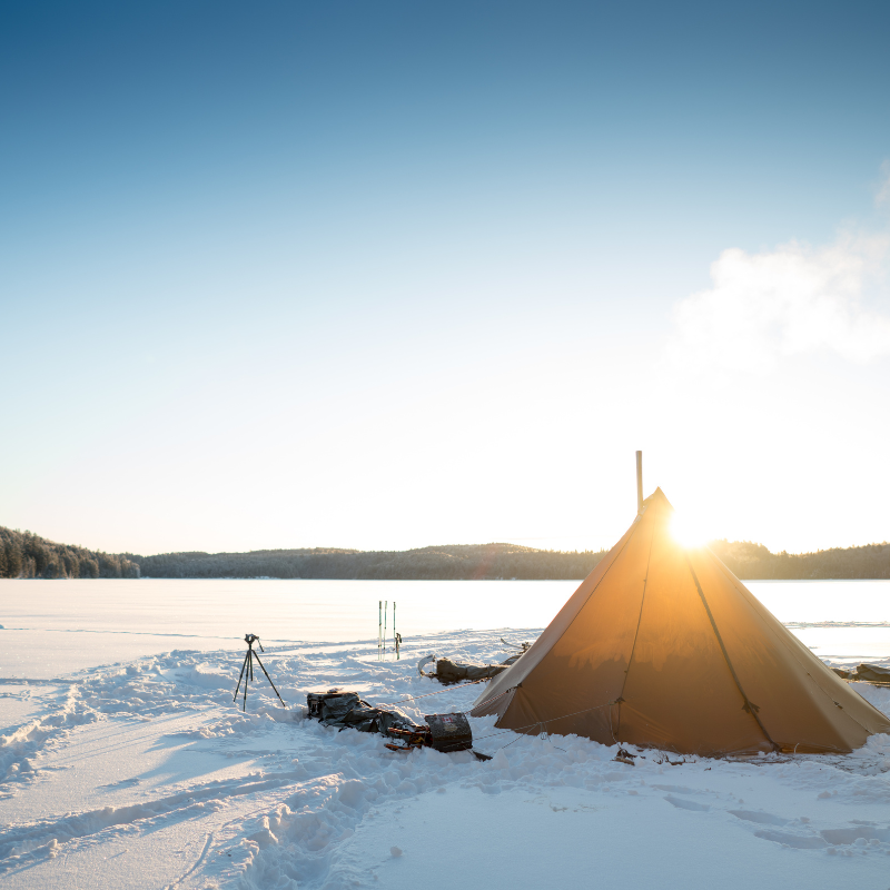Seek Outside 6-person tipi tent pitched in vast snowy valley with sun shining on silnylon canopy and mountain peaks visible on the horizon