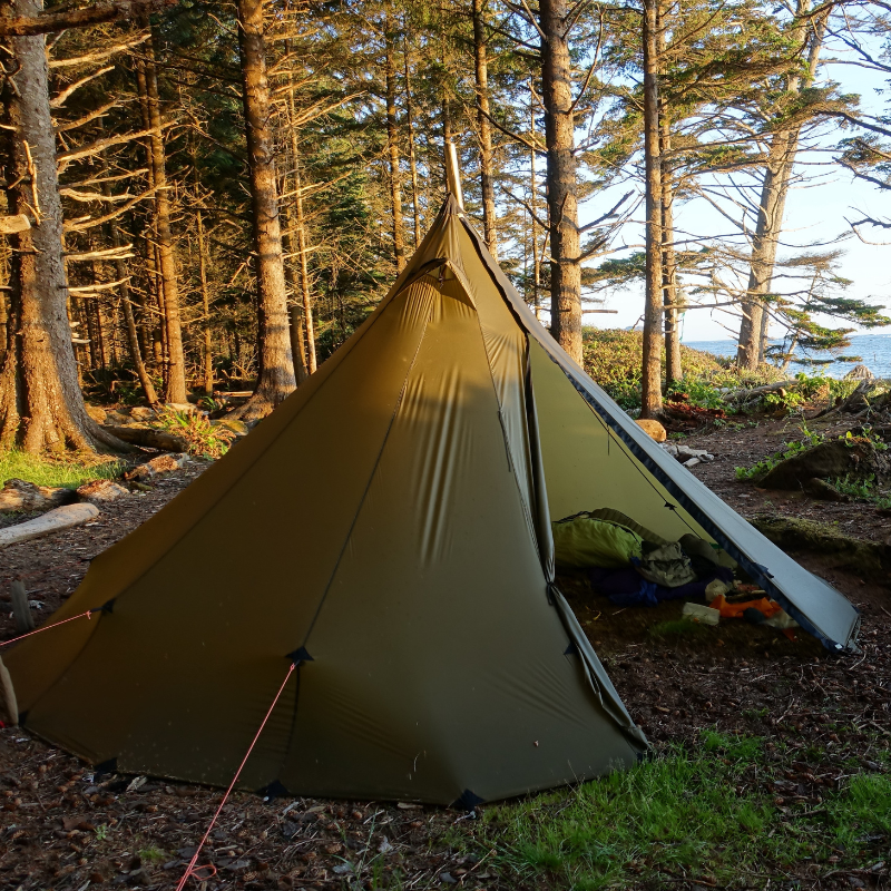 6 person tipi pitched in a damp lakeside campsite, reinforced guy outs deployed for extra weather resistance 