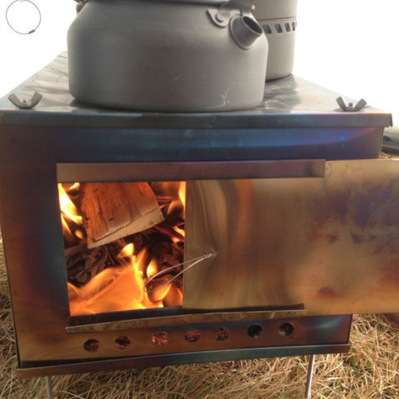 cooking pots on top of XL stove inside tipi tent, fire burning hot inside the stove