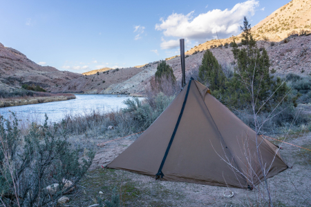 Riverside camp with Seek Outside Cimarron shelter, stove pipe visible, and mountain stream in background