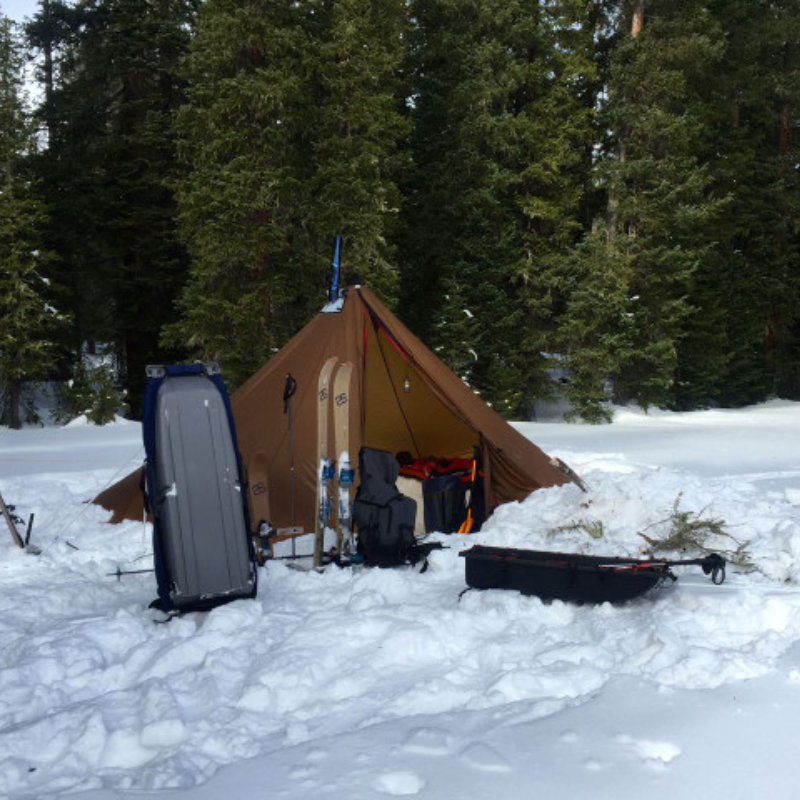 Redcliff pyramid tent in winter storm with stove pipe venting through stove jack and guyouts reinforced for wind