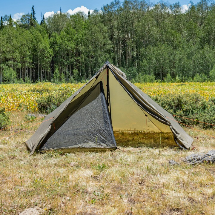 Cimarron half nest inside a green Cimarron shelter in an alpine meadow, the nest takes up half of the shelter allowing for room for two people to sleep in the nest and store gear in the floorless area of the shelter
