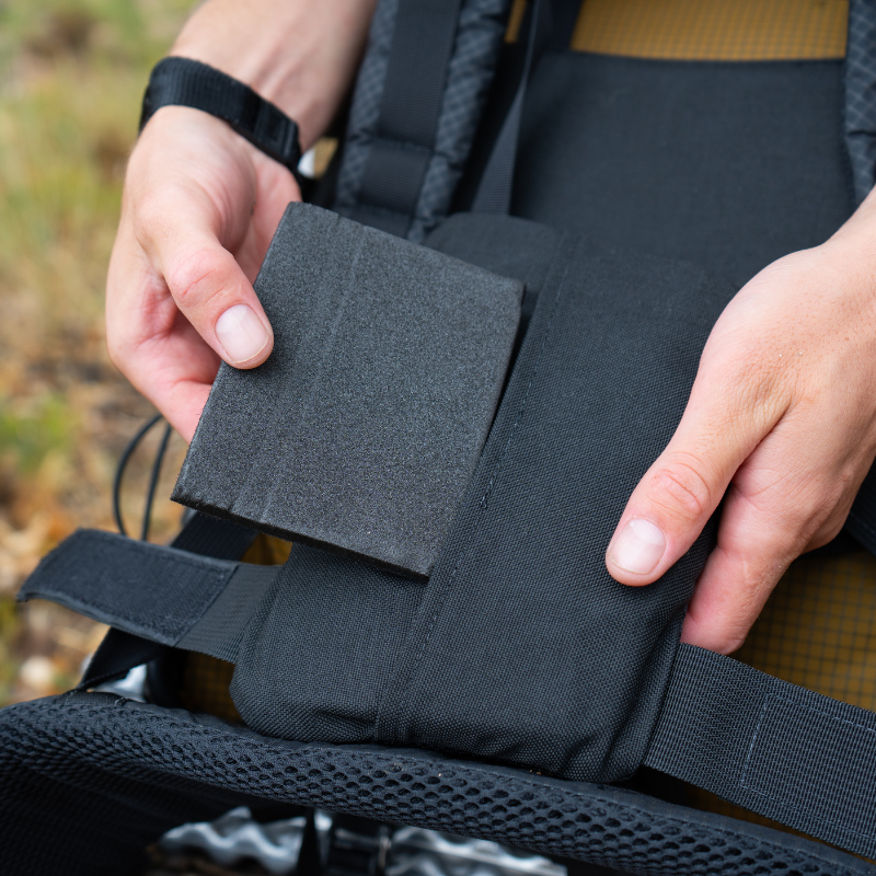 hand adjusting extra removable foam piece on lumbar pad