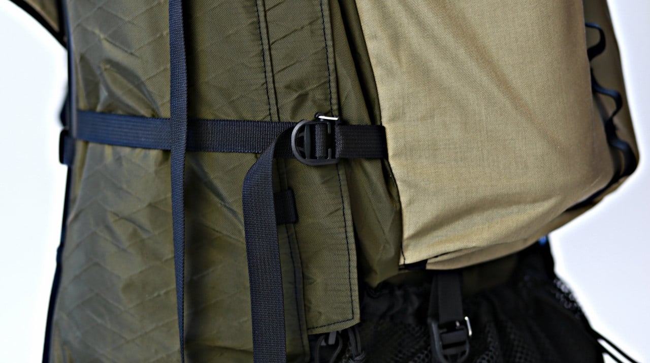 Gatekeeper buckles mounted onto 3/4-inch webbing on a compressed backpack, demonstrating how the locking gate secures the load