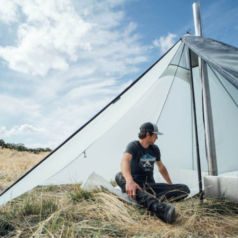 person sits inside of cimarron tent with stove, showing ample headroom