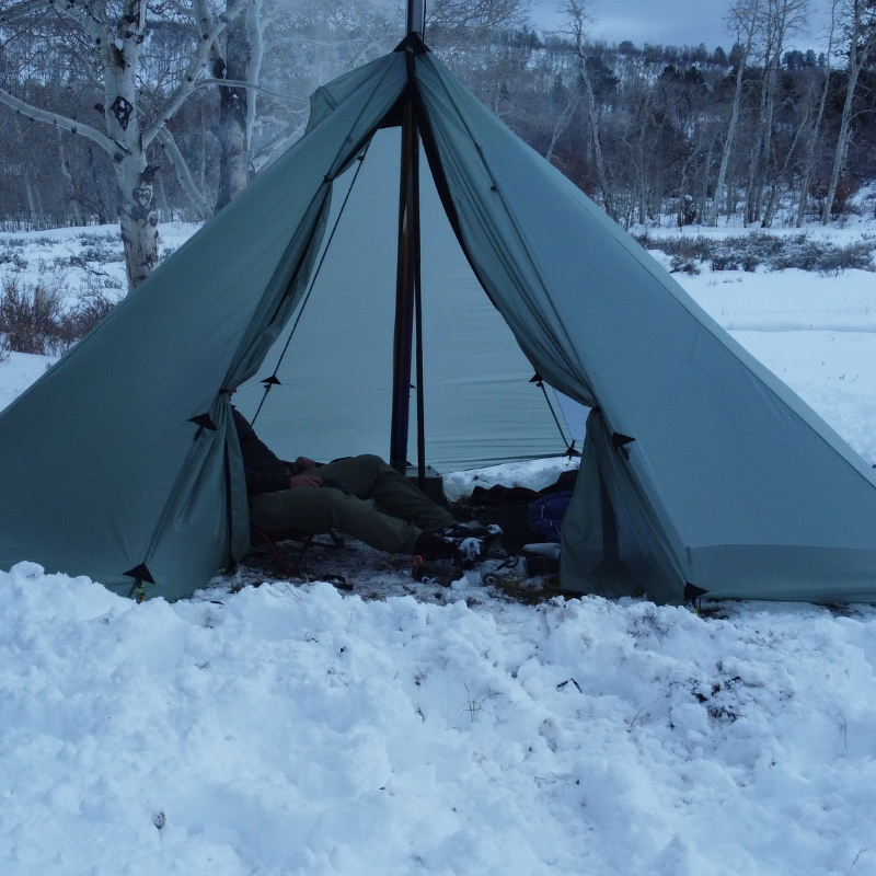 two people keep warm inside a Redcliff Light hot tent
