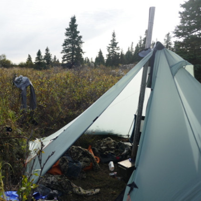 doors open on a Redcliff light pyramid tent revealing stove and camping gear inside