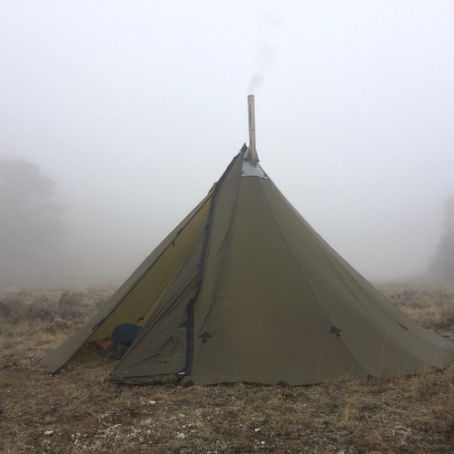 16 Person Tipi with gear inside and stovepipe coming through heat resistant stove jack, surrounded by fog