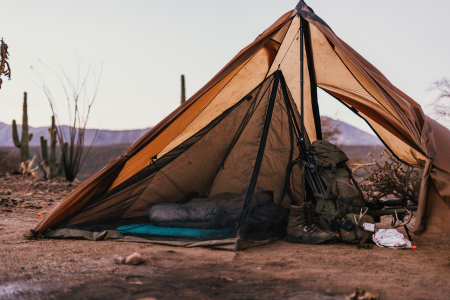 Cimarron Half Nest with sleeping bag inside and hunting pack, rifle, and gear in the tent area outside