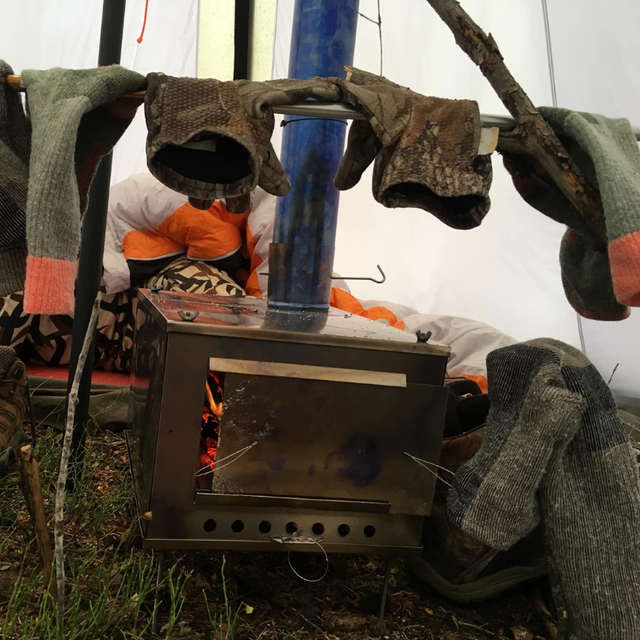 XL stove inside Seek Outside tent, gloves and socks hanging to dry in warmth from stove