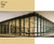 This image showcases a modern glass office building with a portion of its windows covered in Tan window film. The Tan tint creates a striking contrast, casting an appealing hue over the interior space on the left side, while the right side remains untinted and clear. The film enhances both aesthetics and functionality, offering reduced glare and a distinct visual appeal. Above the building image, there is a solid Tan color block labeled "60” Wide Tan 1400," indicating the film’s width and product code.

