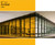 This image showcases a modern glass office building with a portion of its windows covered in Amber window film. The Amber tint creates a striking contrast, casting an appealing hue over the interior space on the left side, while the right side remains untinted and clear. The film enhances both aesthetics and functionality, offering reduced glare and a distinct visual appeal. Above the building image, there is a solid Amber color block labeled "60” Wide Amber 2400," indicating the film’s width and product code.

